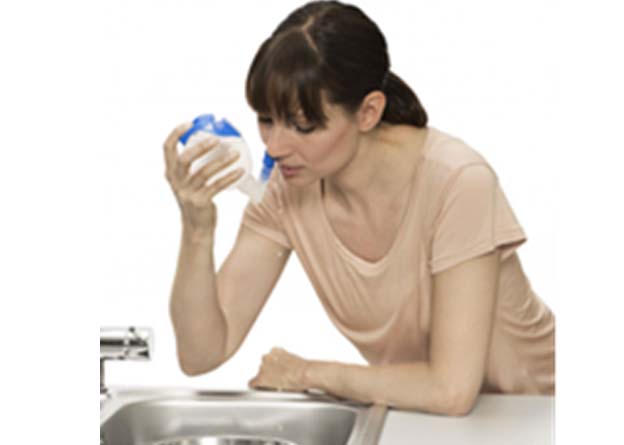 woman using nasal douche containing saline solution